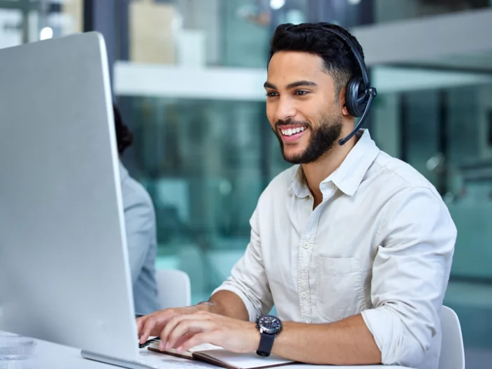 Business man, call center and web support communication at a computer in a office. Phone conversation, smile and male worker with contact us, crm and customer service job in a consulting agency