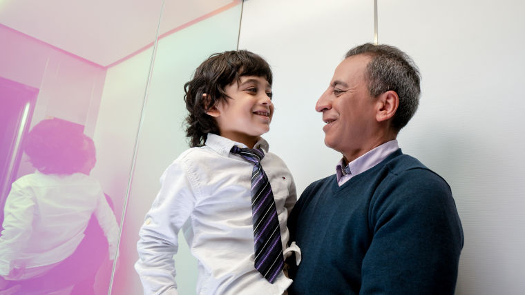Man carrying a boy in elevator.