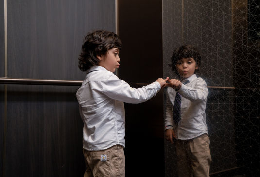 Child in an elevator touching elevator glass.
