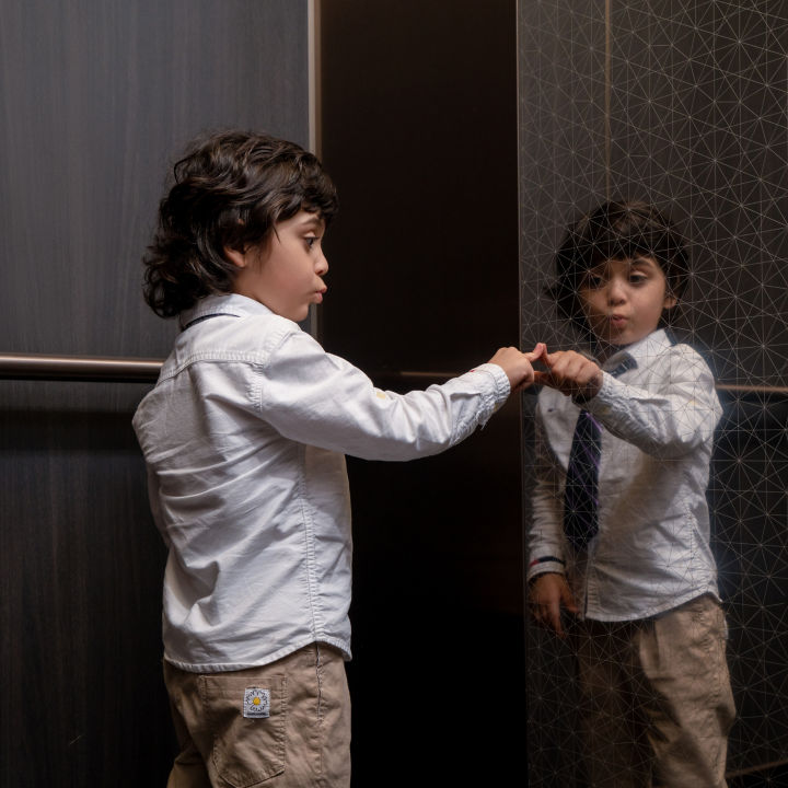 Child in an elevator touching elevator glass.