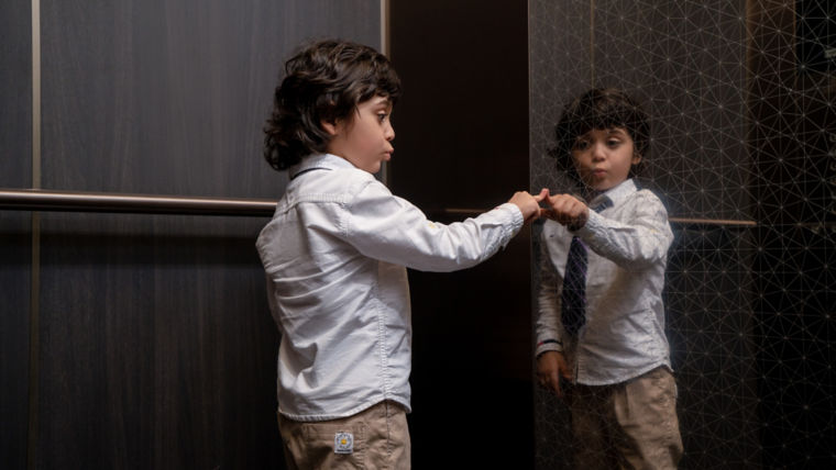 Child in an elevator touching elevator glass.