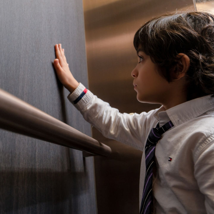 Niño tocando panel interior de la cabina de Elevador residencial KONE MonoSpace® 300 DX