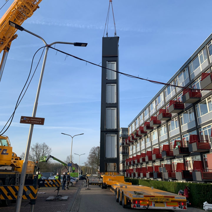 Prefabricated elevator module being lifted by a large crane before installation.