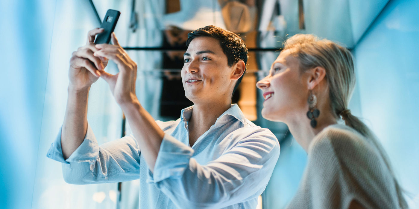 Two people taking pictures with a smartphone in an elevator.