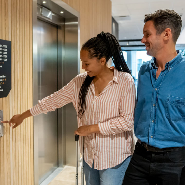 Couple with luggage pressing the elevator button
