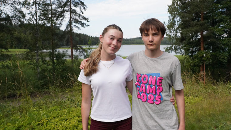 Lacey and Valtteri standing by the lake arms around shoulders.