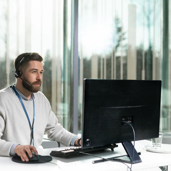Hombre con auriculares frente a una computadora - KONE Servicio al cliente