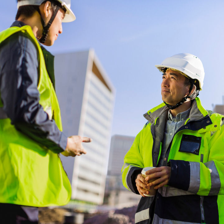 Workers talking at building construction site.