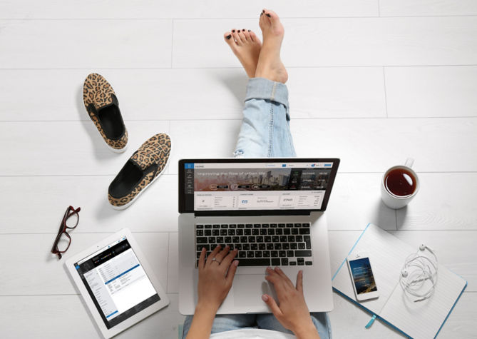Person working on the floor - KONE Online on laptop screen and KONE Mobile on smartphone screen.