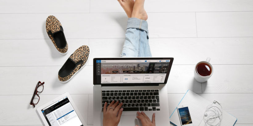 Person working on the floor - KONE Online on laptop screen and KONE Mobile on smartphone screen.