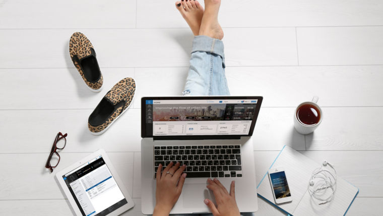 Person working on the floor - KONE Online on laptop screen and KONE Mobile on smartphone screen.