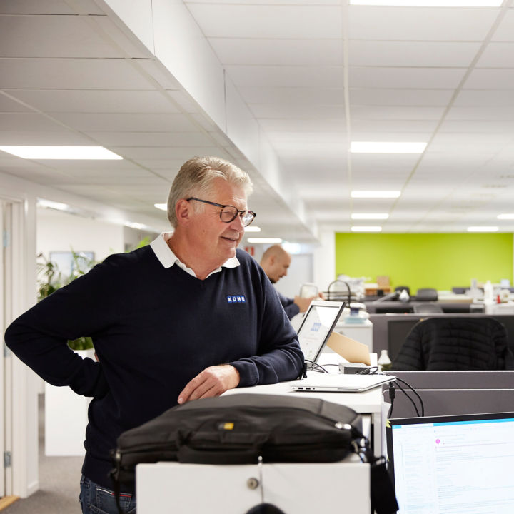 Stefan Wallin discussing with a colleague working at his desk at KONE's Årsta office.