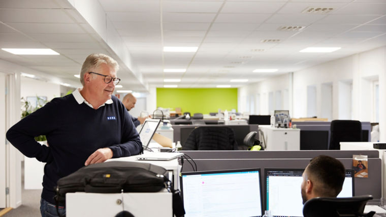 Stefan Wallin discussing with a colleague working at his desk at KONE's Årsta office.