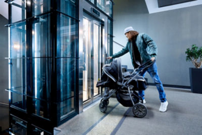 Man with a baby stroller pushing an elevator call button in a residential stairway