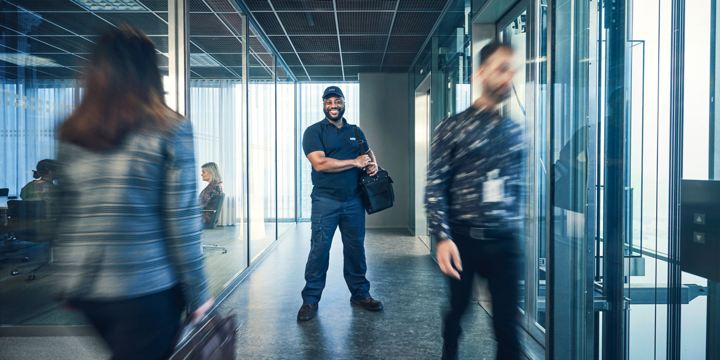 KONE service technician standing in a modern glass office.
