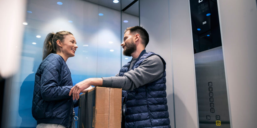 Mujer y hombre dentro de un elevador sosteniendo una caja - elevador residencial KONE