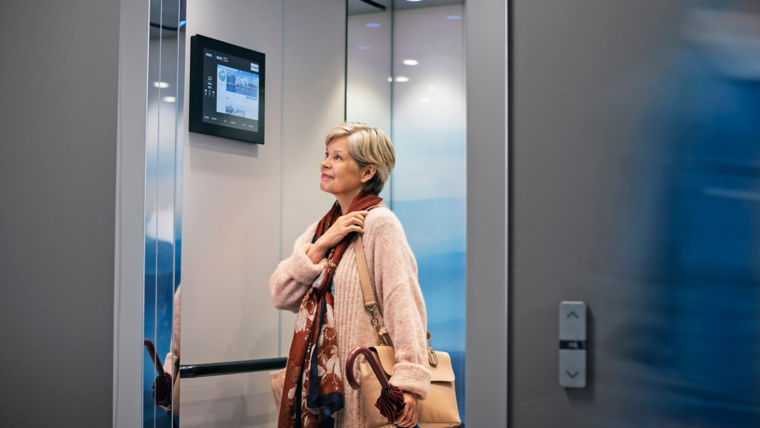 Elderly woman in elevator looking at an information screen