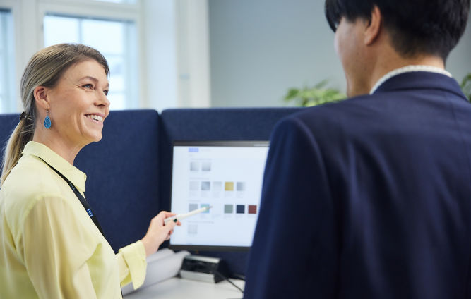 Two colleagues conversing in front of computer screen.