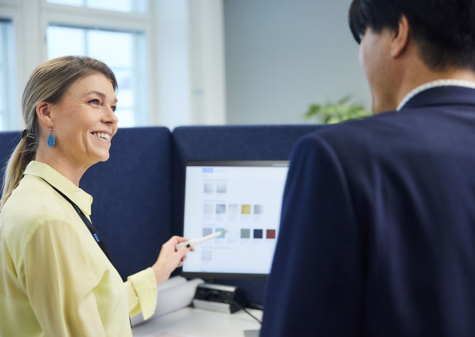 Two colleagues conversing in front of computer screen.