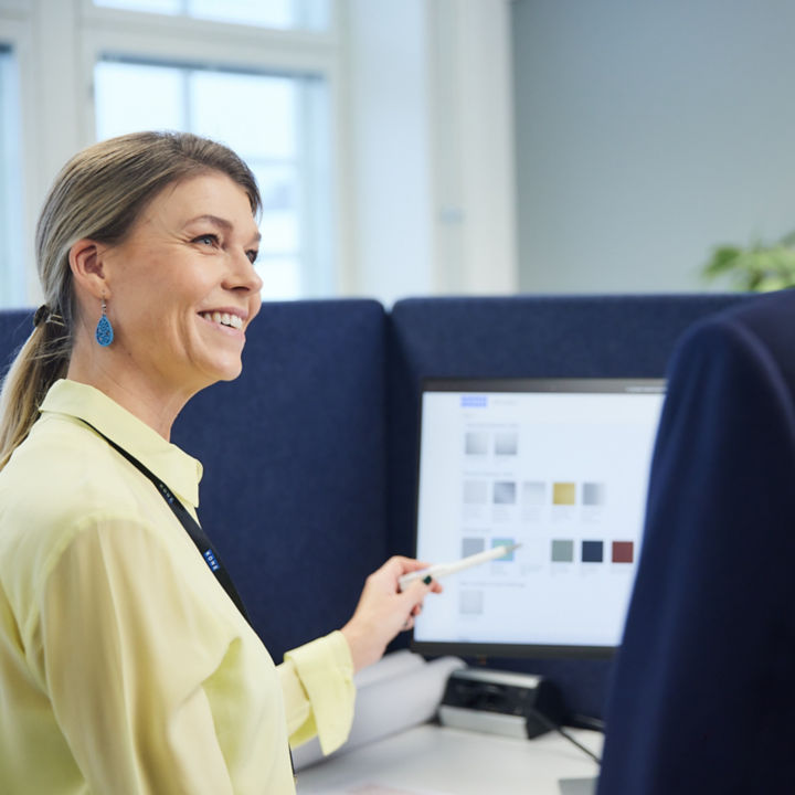Two colleagues conversing in front of computer screen.