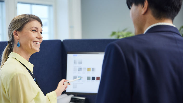 Two colleagues conversing in front of computer screen.