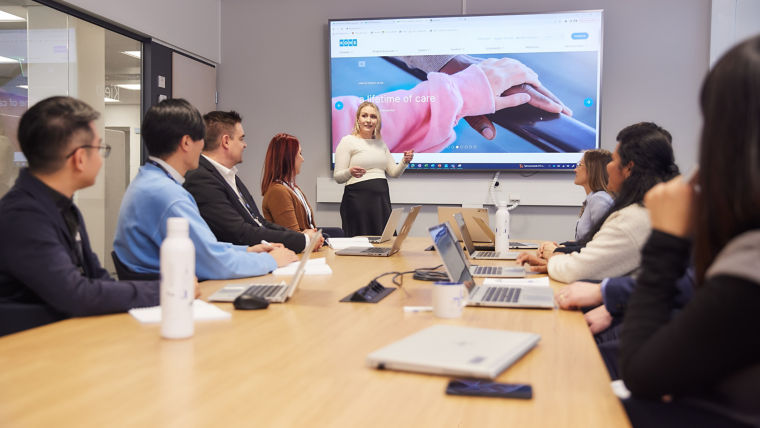 Group of KONE employees having a meeting and watching presentation in conference room.