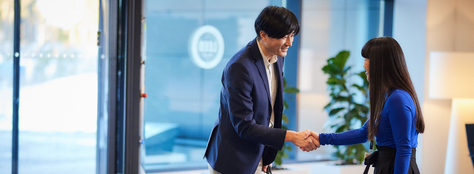 Two people shaking hands in lobby before business meeting.