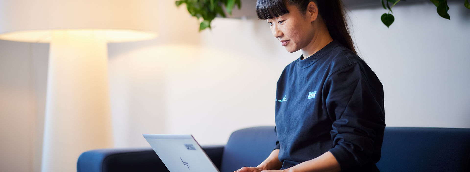 KONE employee working in front of laptop while sitting on a couch.