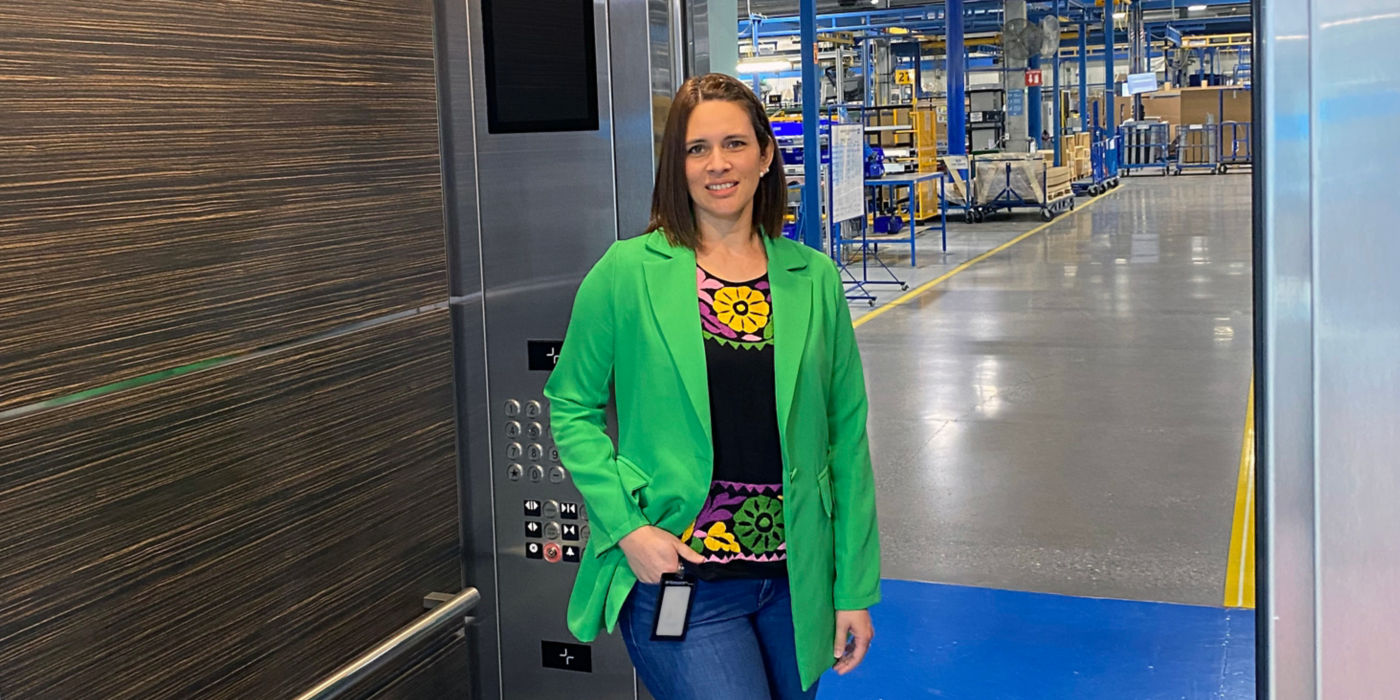 KONE Agile Coach Nadia Lizarraga in an elevator with a factory view in the background.
