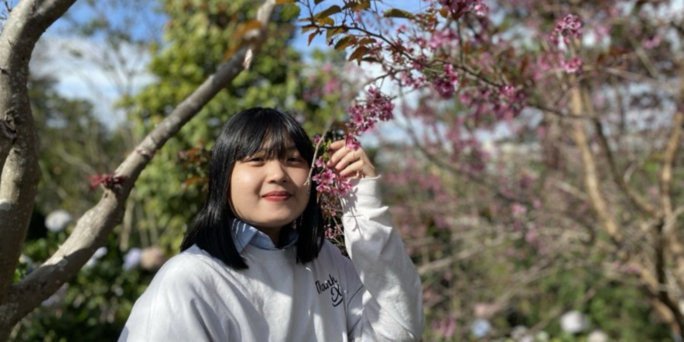 KONE Service Technician Tran Le Nhu Binh holding a blossoming branch of a cherry tree.