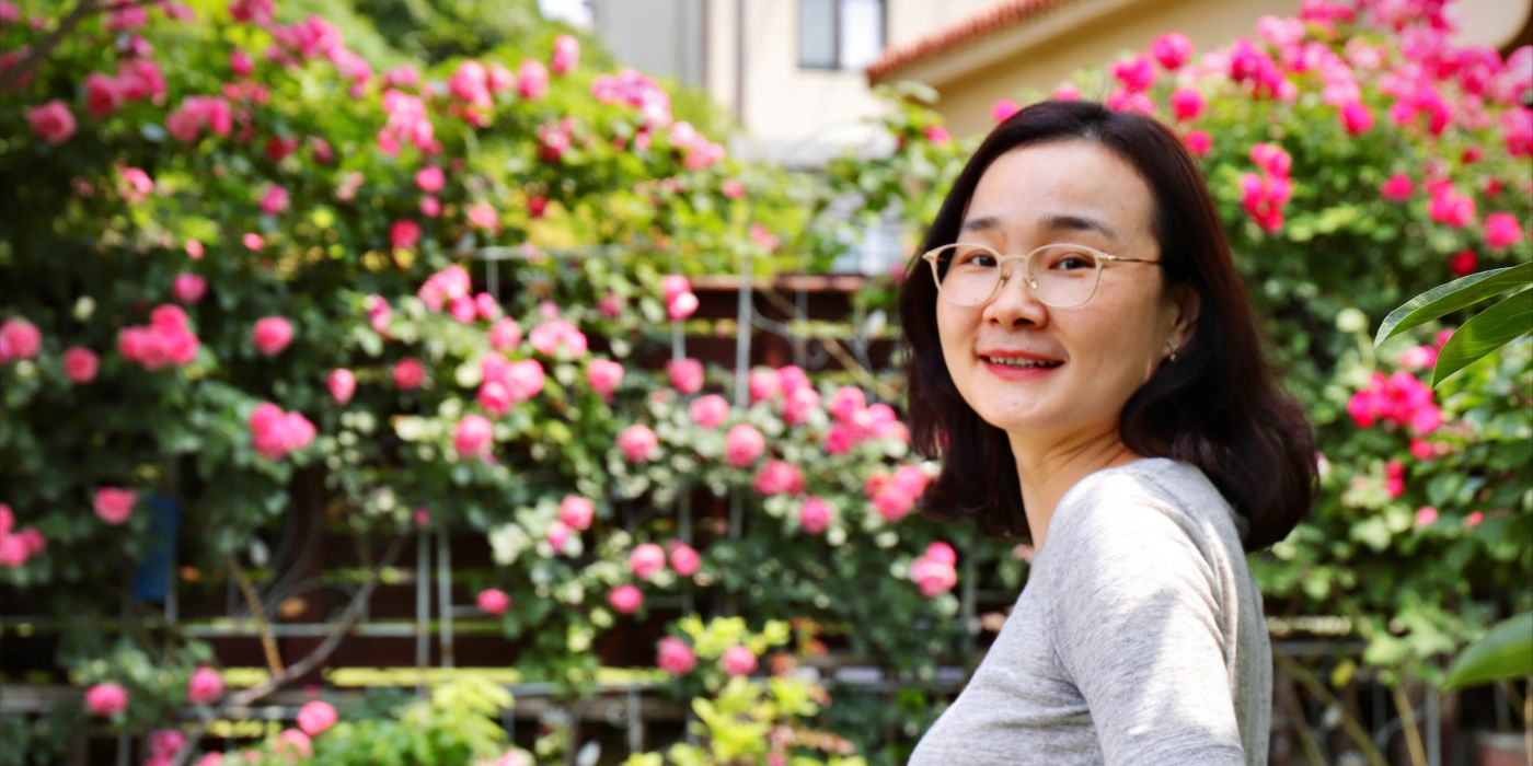 KONE Finance Director Xiamin Xu with blossoming trees in the background.