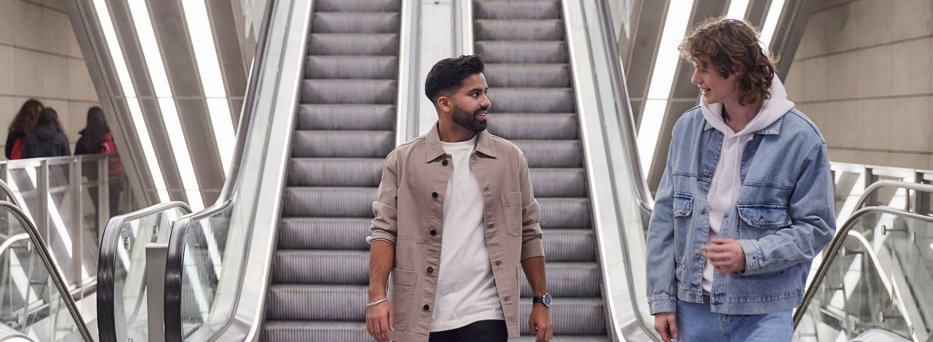 Two men walking out of the escalator.