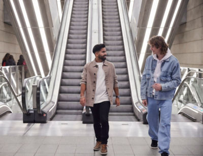 Two men walking out of the escalator.