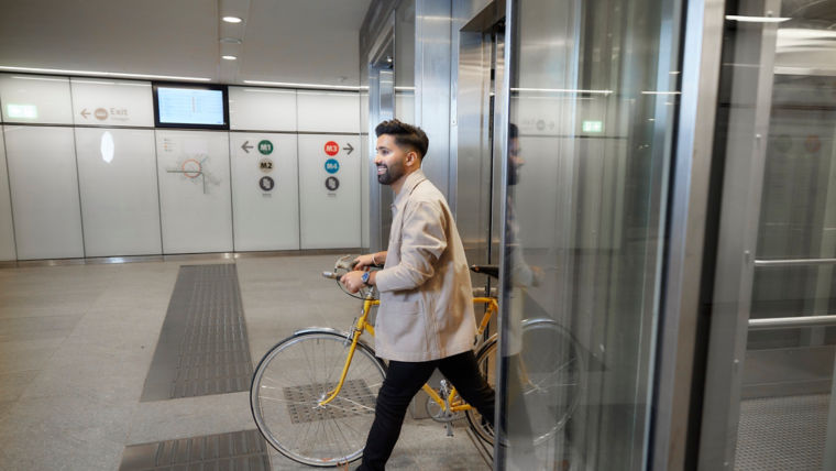 Man with bike walking out of the elevator at a metro station