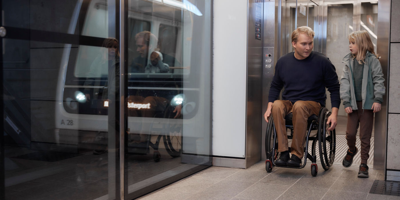 Man in a wheelchair with a girl exiting an elevator