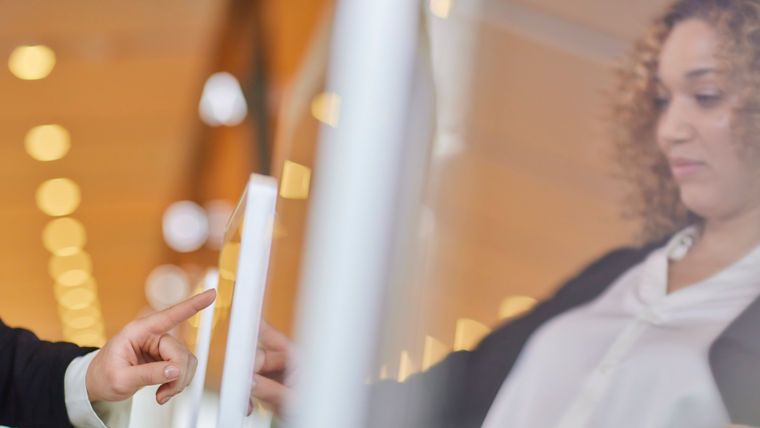 Woman using KONE destination touchscreen.