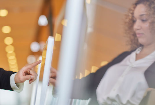 KONE - Woman using touch screen device to call an elevator.