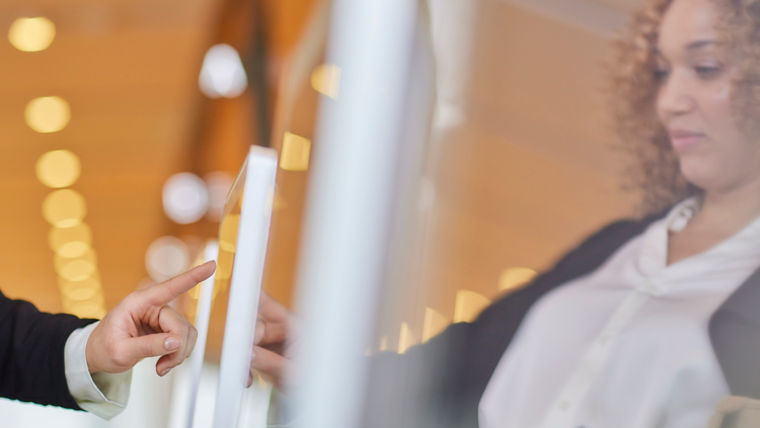 KONE - Woman using touch screen device to call an elevator.