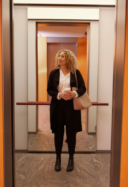 Business woman inside an elevator car.
