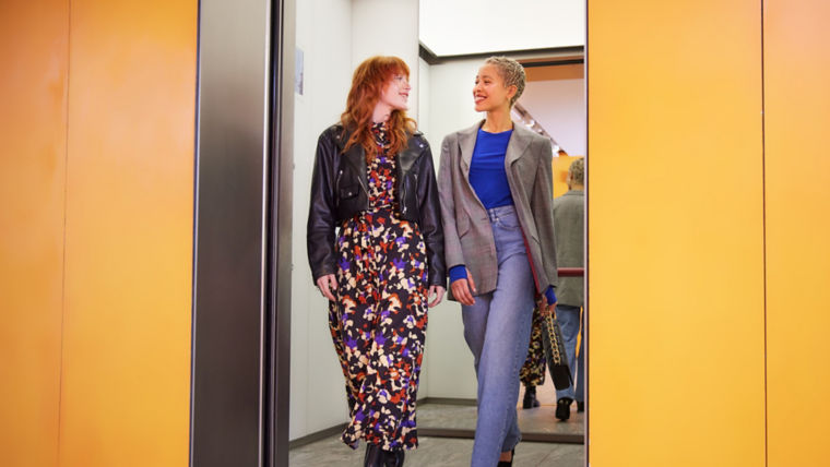 KONE - Two women walking out of an elevator into a hallway.