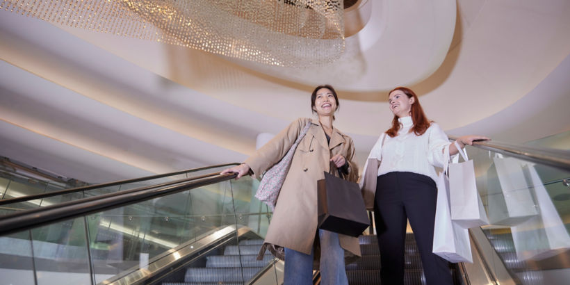 Kaksi naista seisomassa KONEen liukuportaissa ostoskeskuksessa.