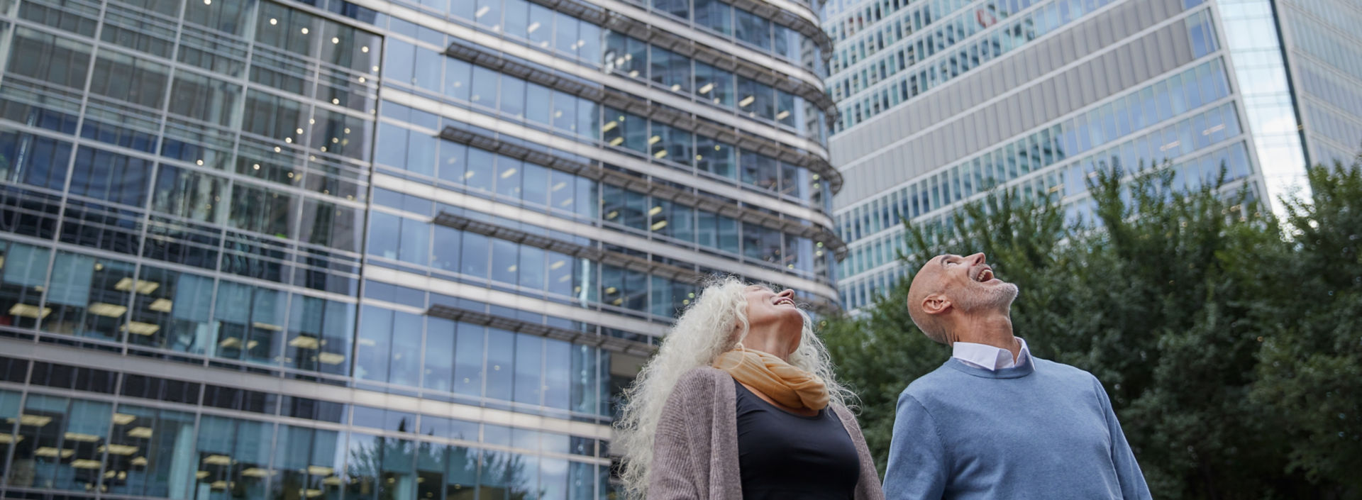 Woman and man looking up at hight rising office buildings from outside.