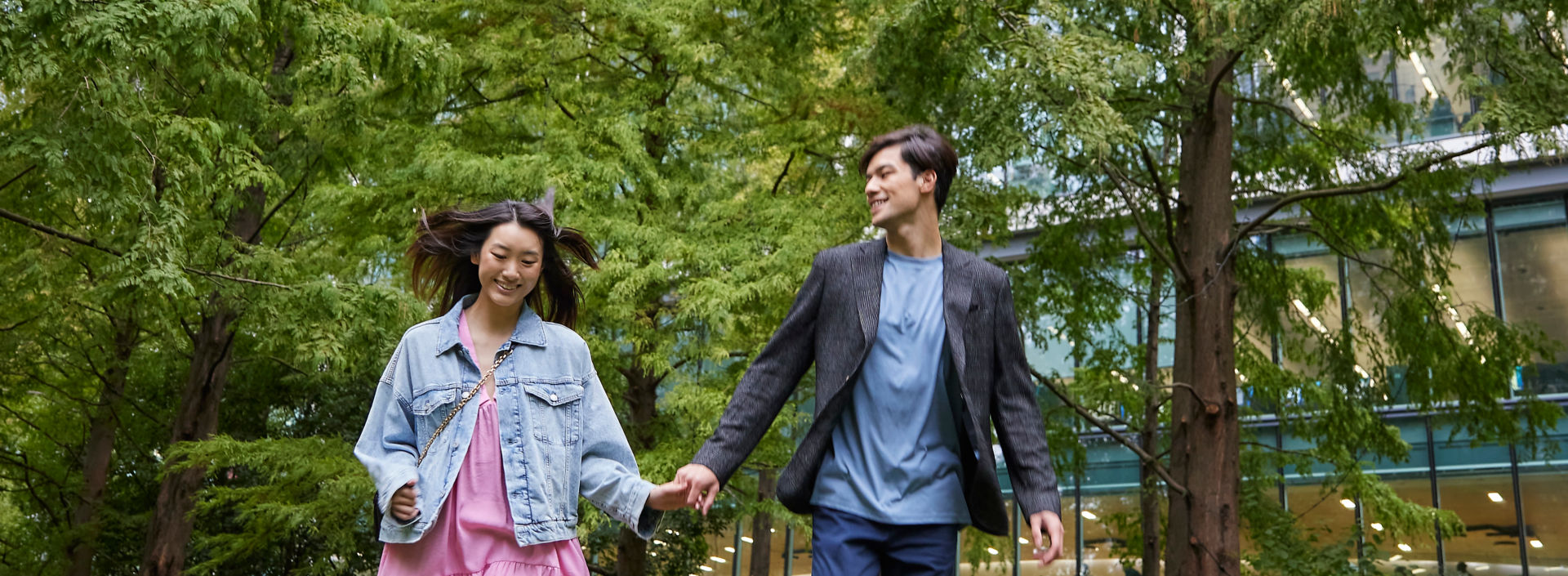 Happy Asian couple running in the park next to a high-rise building