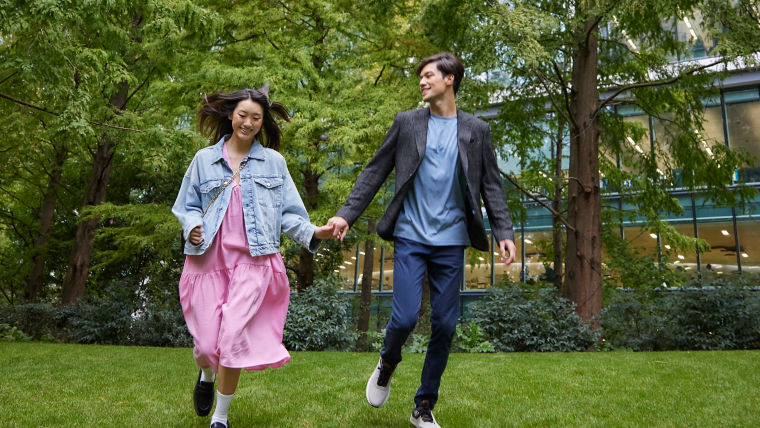 Happy Asian couple running in the park next to a high-rise building