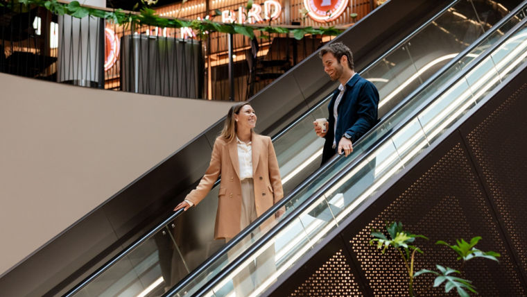 Mujer y hombre bajando escaleras eléctricas - KONE Sustentabilidad