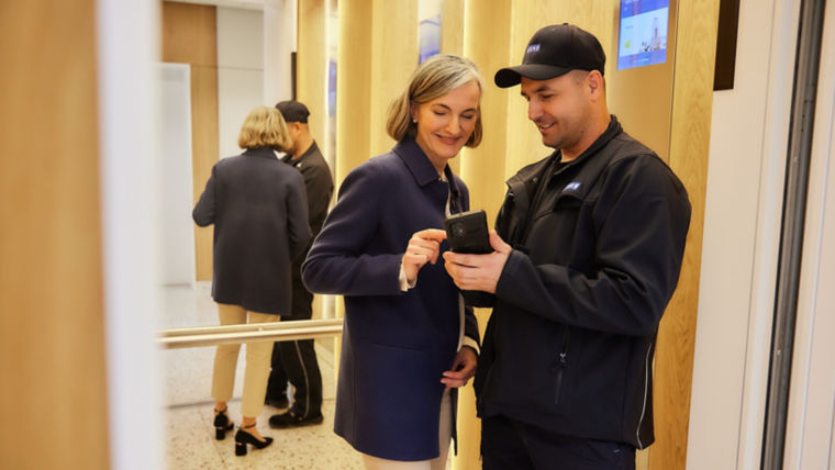 KONE technician showing mobile app to a person in elevator.