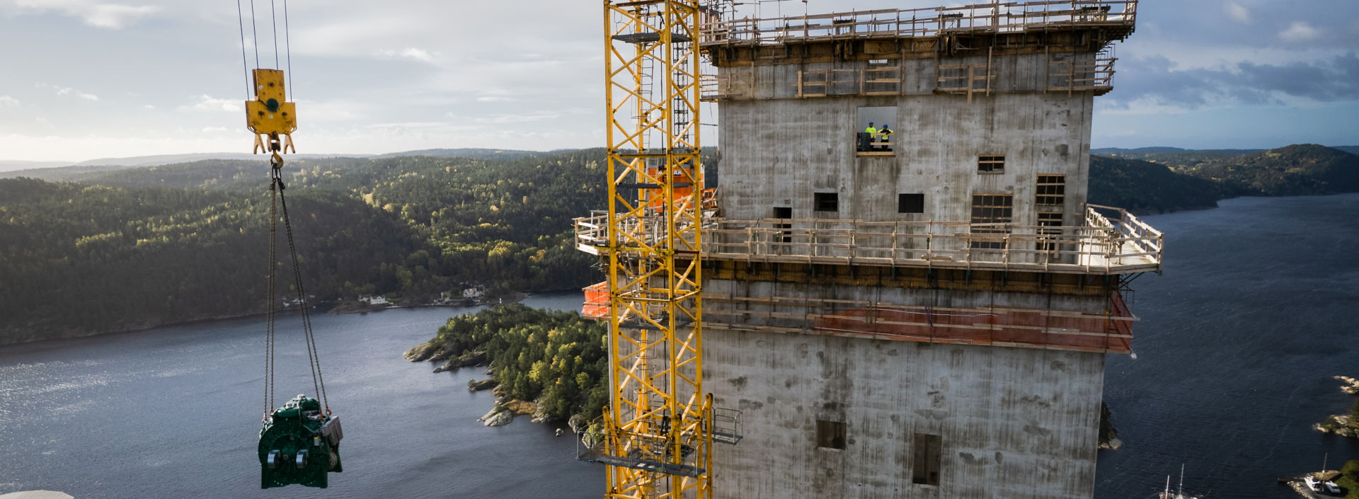 Construction site tall tower and crane hoisting an MX100 machine into place.