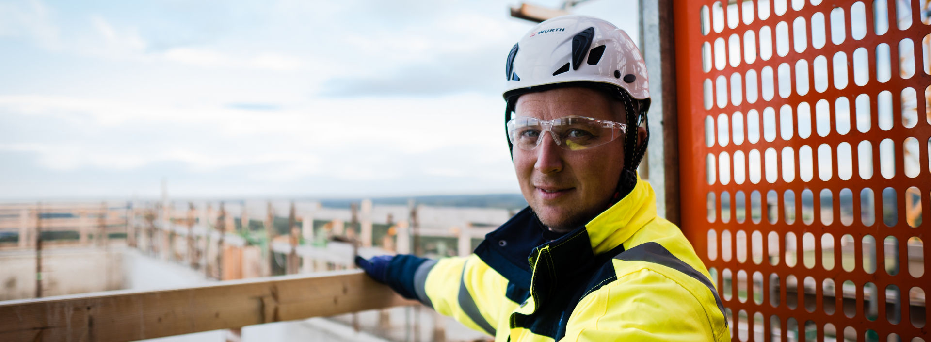 Male construction site worker with helmet and safety glasses.