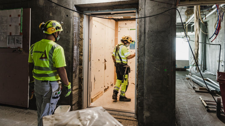 Men at construction site working on elevator.