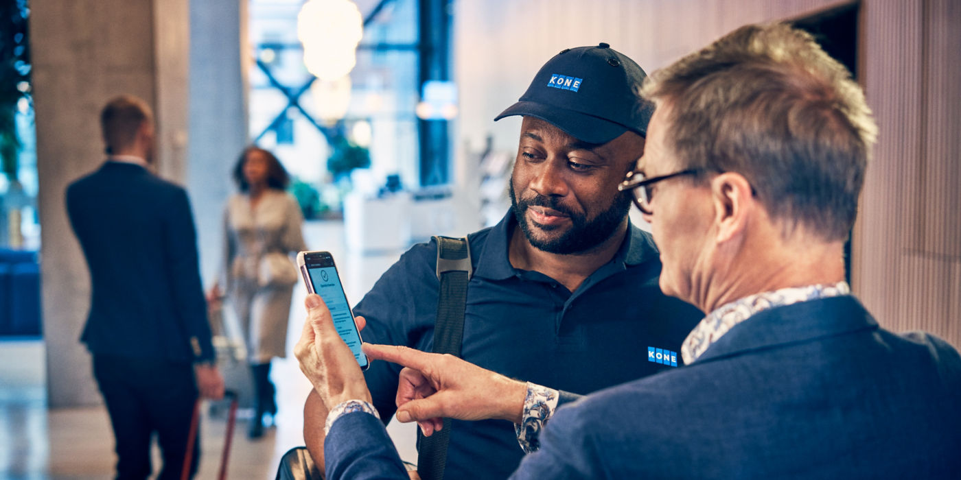 Maintenance technician and customer looking at smartphone.